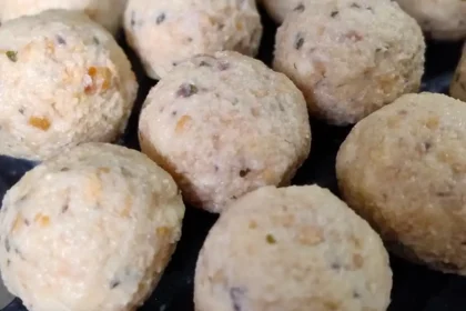 Viele noch ungekochte Semmelknödel liegen in Reihen nebeneinander auf einem Brett.