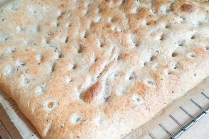 Ein frisch gebackenes Fladenbrot so groß wie ein Backblech liegt auf einem Gitter zum Auskühlen