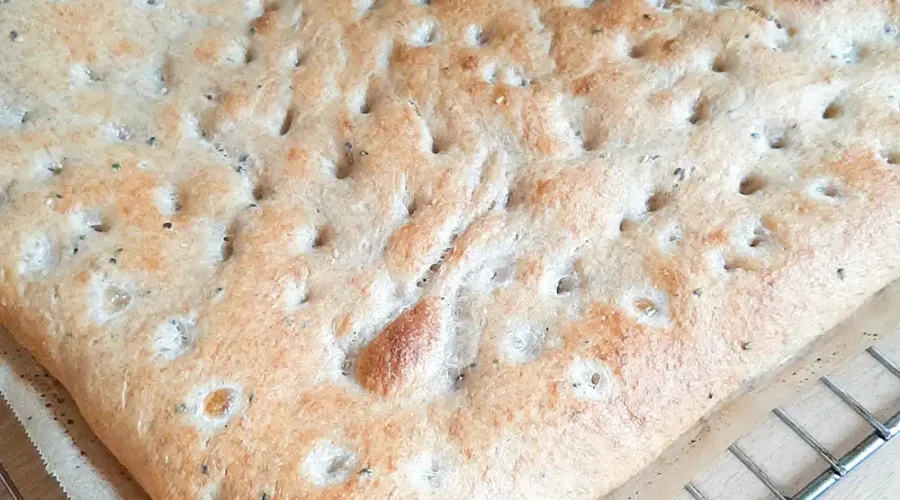 Ein frisch gebackenes Fladenbrot so groß wie ein Backblech liegt auf einem Gitter zum Auskühlen