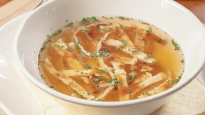 Weiße Schüssel gefüllt mit Brühe und fein geschnittenen Flädle