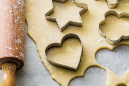 Ausgerollter Teig, aus dem Sterne und Herzen ausgestochen werden.
