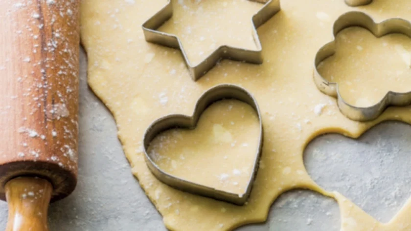 Ausgerollter Teig, aus dem Sterne und Herzen ausgestochen werden.