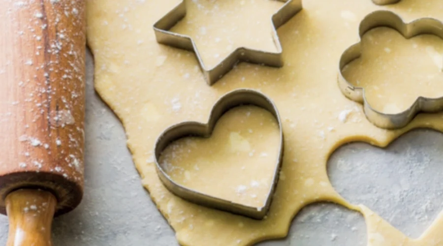 Ausgerollter Teig, aus dem Sterne und Herzen ausgestochen werden.