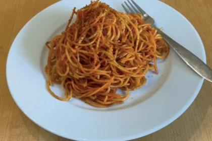 Tomatige Spaghetti auf einem weißen Teller mit Gabel