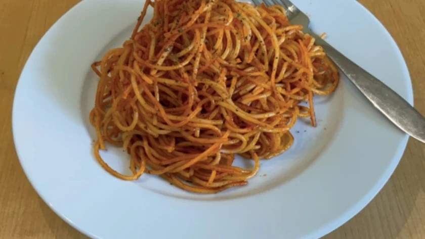 Tomatige Spaghetti auf einem weißen Teller mit Gabel