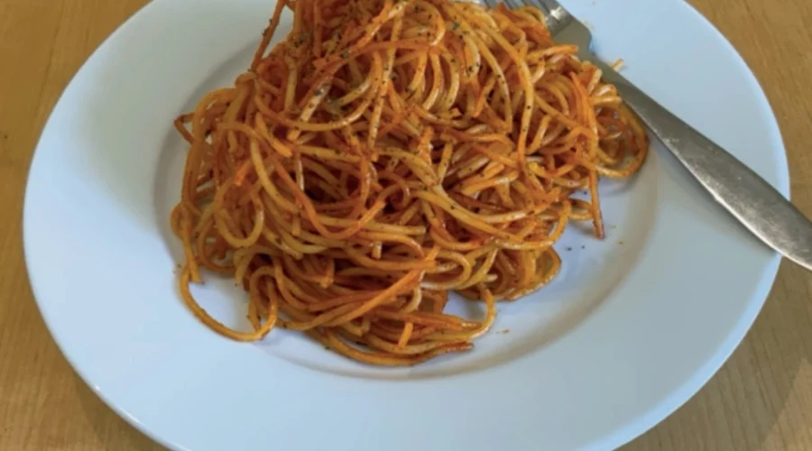 Tomatige Spaghetti auf einem weißen Teller mit Gabel