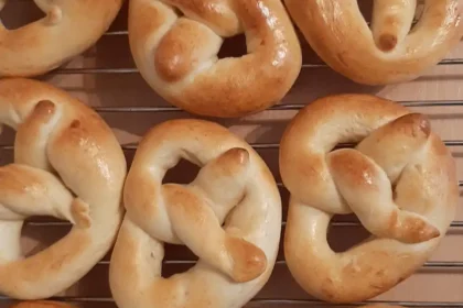 Mehrere kleine goldbraun gebackene Brezeln liegen nebeneinander auf einem Gitter zum Auskühlen.