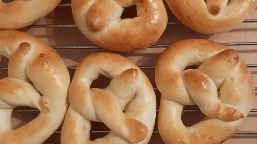 Mehrere kleine goldbraun gebackene Brezeln liegen nebeneinander auf einem Gitter zum Auskühlen.