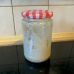 Ein Glas mit frischem Sauerteig-Ansatz steht auf der Arbeitsplatte.
