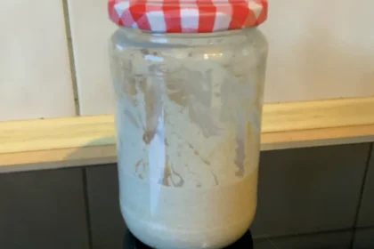 Ein Glas mit frischem Sauerteig-Ansatz steht auf der Arbeitsplatte.