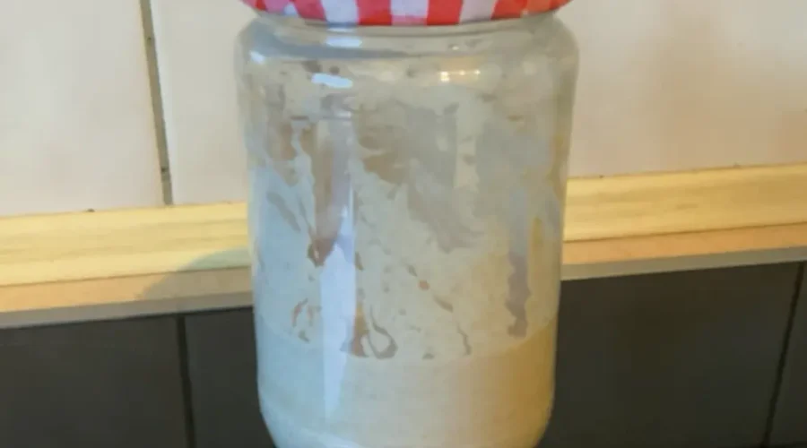 Ein Glas mit frischem Sauerteig-Ansatz steht auf der Arbeitsplatte.